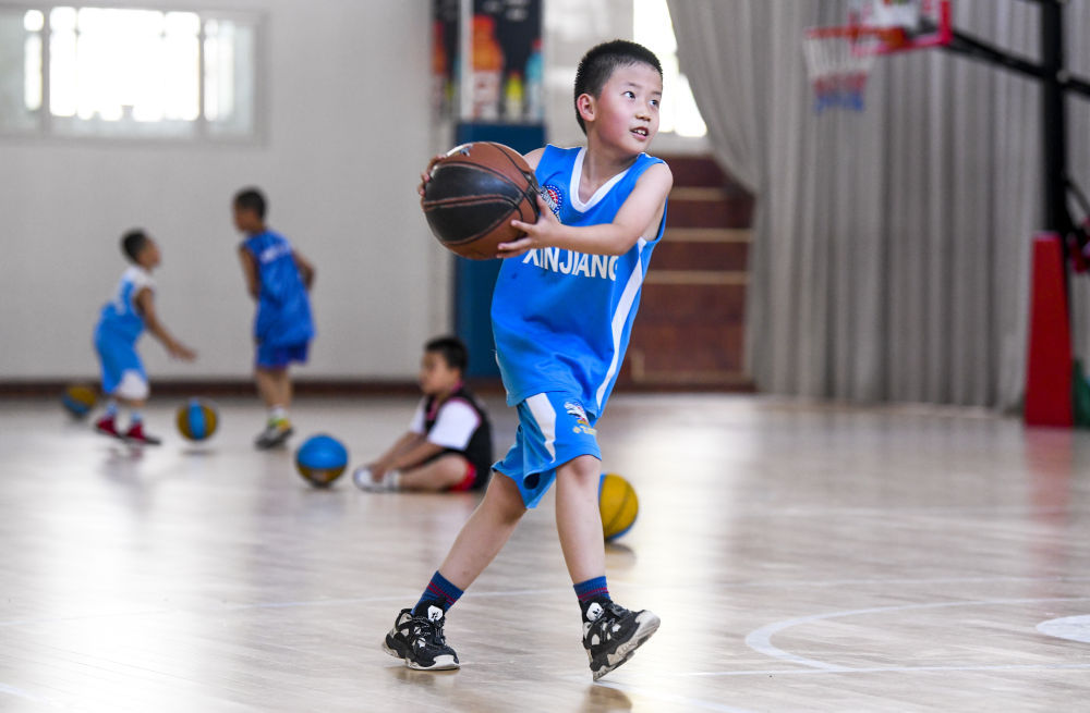 6月18日，在新疆广汇小飞虎篮球训练营内，来自乌鲁木齐市第十三小学一年级（5）班的于淼翰轩在练习打篮球。