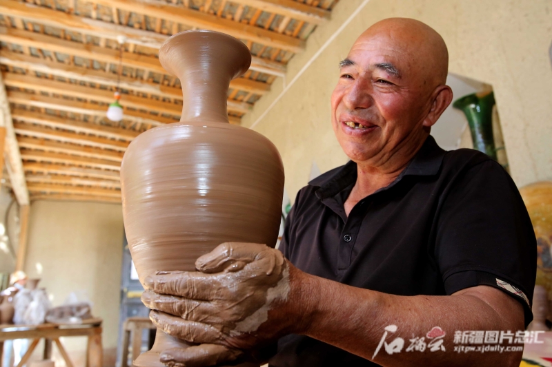 6月19日，英吉沙县芒辛镇恰克日库依村土陶非遗传承人阿卜杜热合曼·麦麦提敏在欣赏刚制作的土陶作品。石榴云/新疆日报记者 蔡增乐 摄