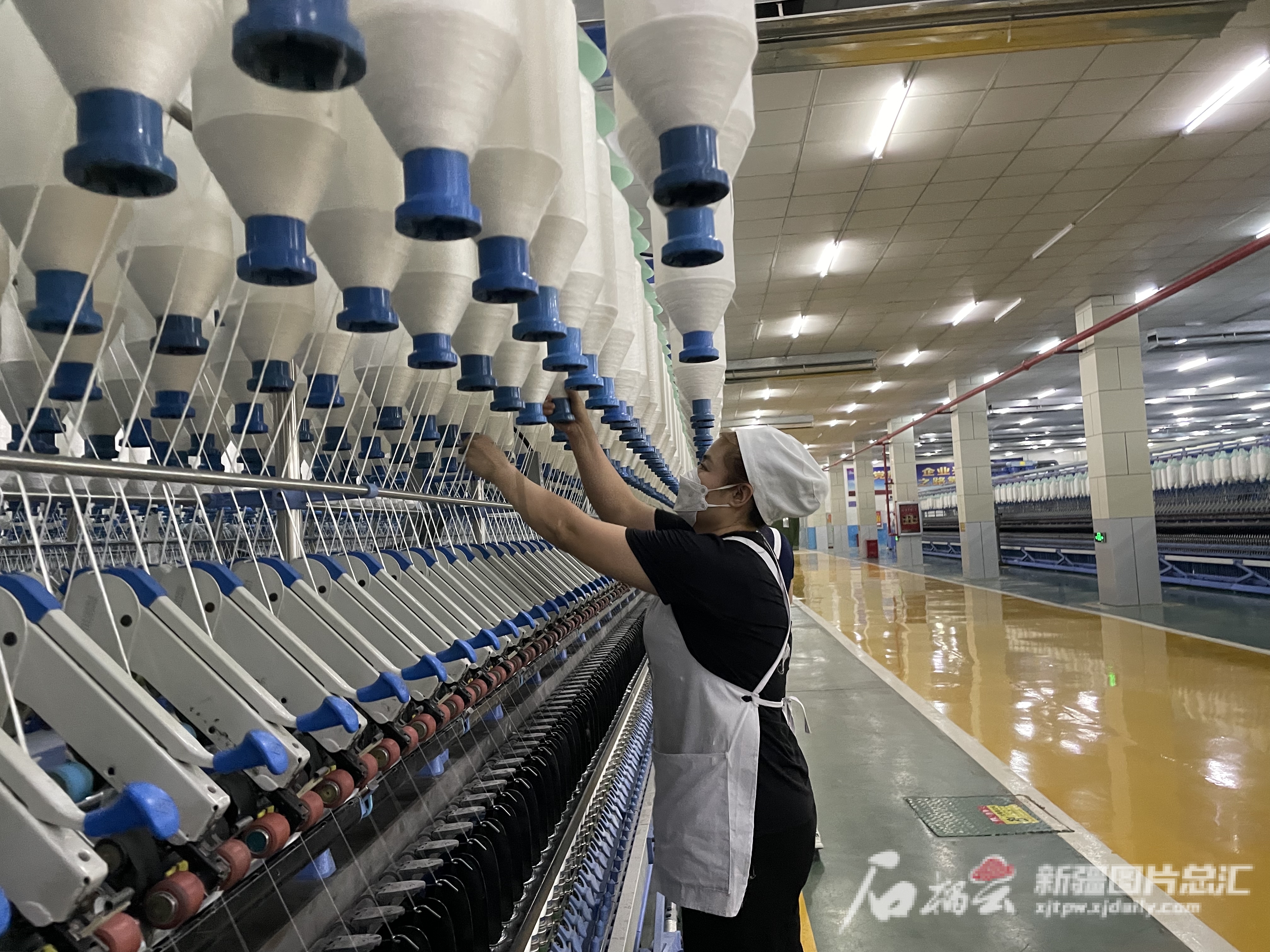 12月15日，在新疆兴泰纤维科技有限公司生产车间里，细纱挡车工正在进行换纱工作。马艳琳 摄
