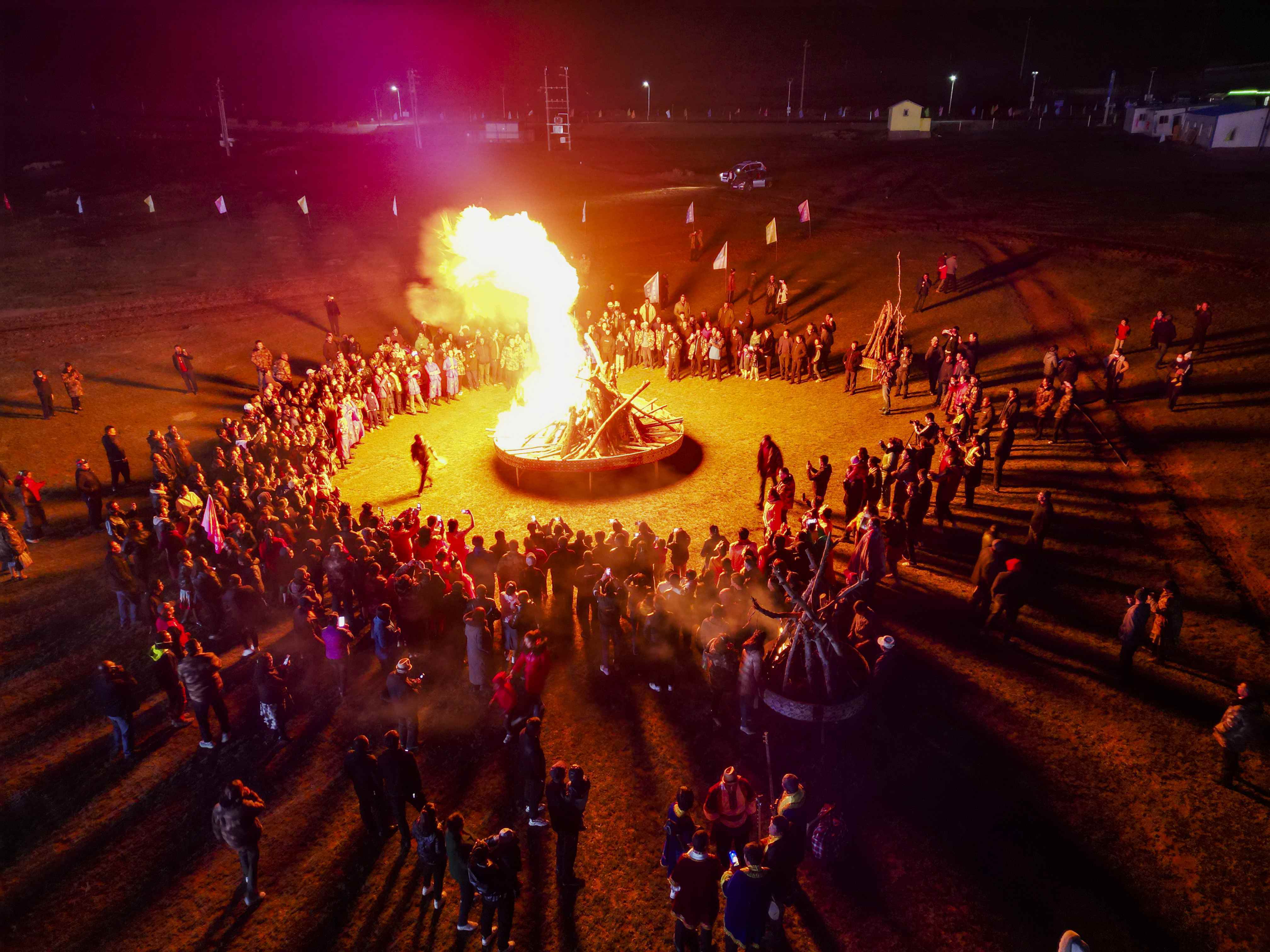 游客在和田地区策勒县板兰格景区举办的一场篝火晚会上载歌载舞（5月30日摄，无人机照片）。（摄影：新华社记者郝昭）