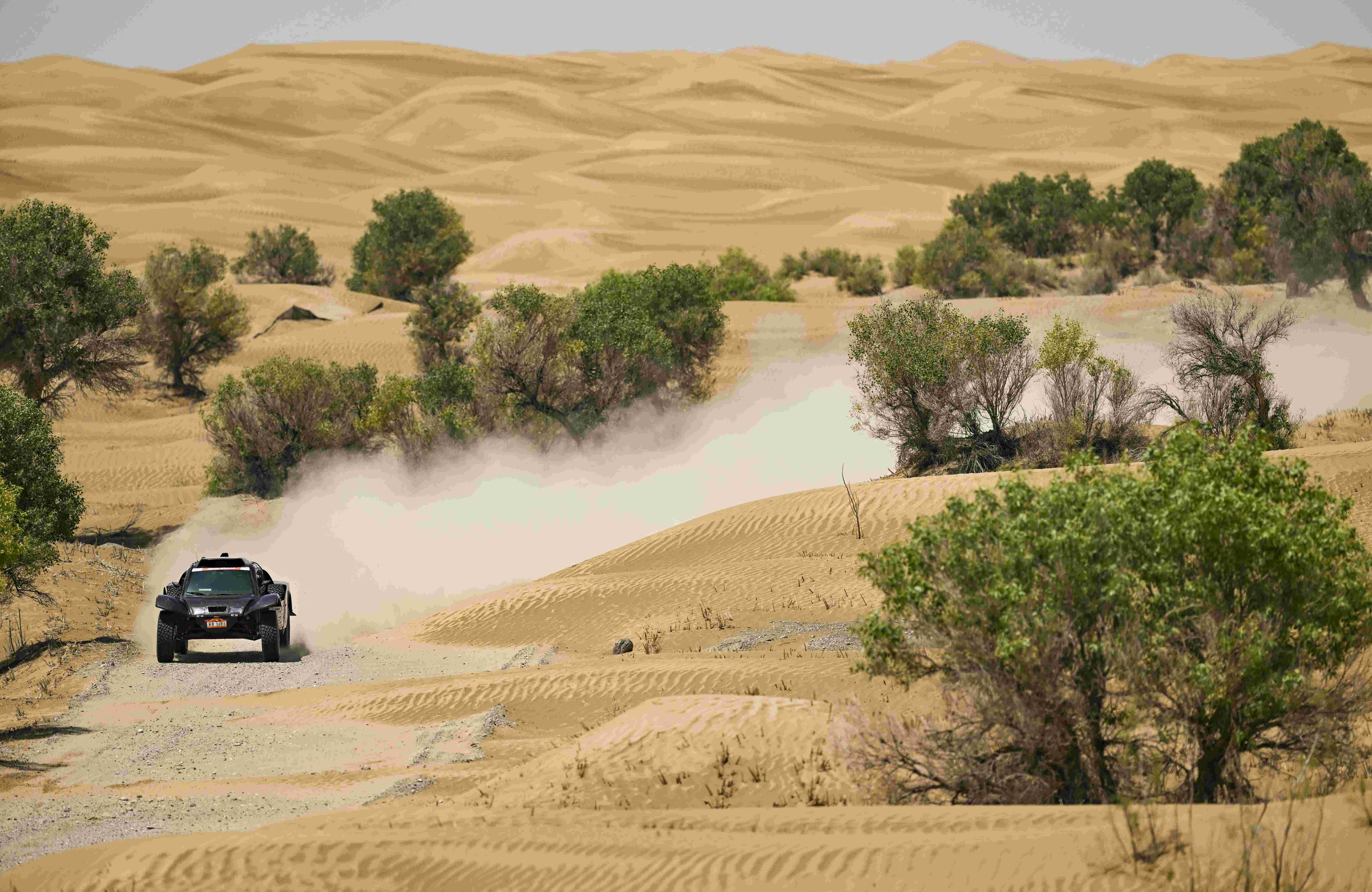 参与2023年中国环塔（国际）拉力赛的车手驾驶赛车疾驰在和田地区墨玉县的沙漠中（5月28日摄）。（摄影：新华社记者胡虎虎）