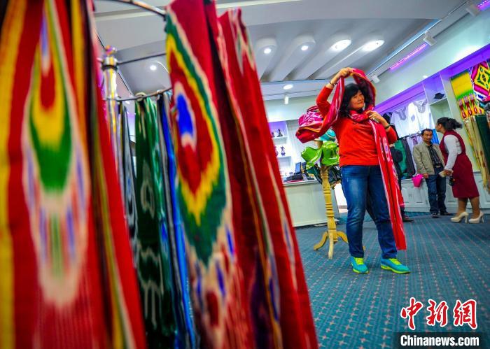 一位游客正在选购艾德赛斯丝绸，古老的纺织工艺每年给吉亚乡带来约3万人的游客，推动当地经济增长。　刘新 摄