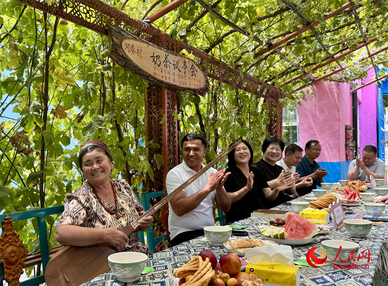 在惠远镇河巷村举行的“奶茶会”上，村民弹起都塔尔，唱出幸福生活。人民网 李龙摄